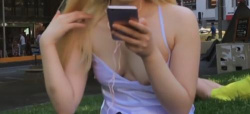電話している芝生に座る派手な化粧のお姉さんの胸チラ・パンチラを盗撮！の画像
